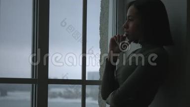 沮丧沮丧的女人靠在窗户上。