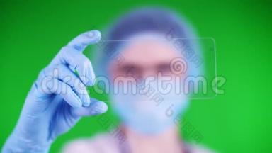 绿色背景。 特写镜头，医生戴着医疗帽、口罩、蓝色医疗手套，手里拿着一张玻璃卡片