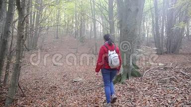 在春天带着背包在森林里散步的女人，慢镜头