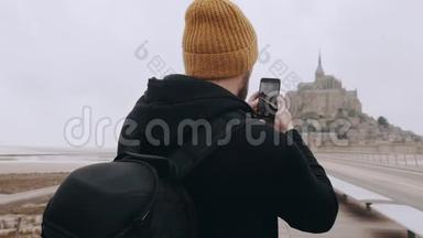 后景快乐兴奋的游客男子拍摄智能手机<strong>视频</strong>史诗山圣米歇尔<strong>城堡</strong>在诺曼底慢动作。