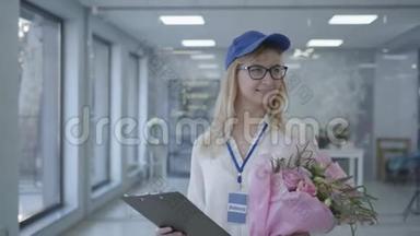 年轻的微笑女孩戴着眼镜和帽子，在送货服务中工作，女员工花束给