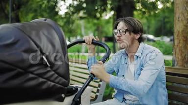 累得昏昏欲睡的男人坐在公园长椅上晃着婴儿车，为人父母累得精疲力尽