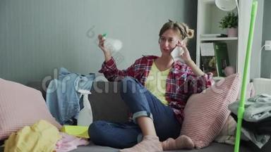 漂亮的年轻女子在打扫完房间并通了电话后正在沙发上休息