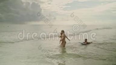 快乐的年轻女子在美国巴拿马城海滩的海水中与她的孩子玩耍