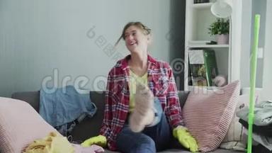 戴着手套的微笑女人坐在沙发上，在打扫房间后放松