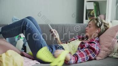 年轻女子正在听音乐，打扫完房子后躺在沙发上休息