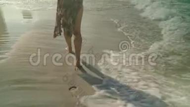 在夏天的海滩上，年轻女子沿着海水和沙子散步，闭上双腿。 旅行概念。