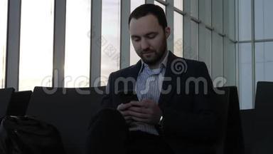 商务人员坐在机场大厅时通过手机<strong>发信息</strong>