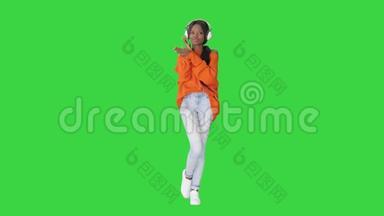 快乐美丽的年轻<strong>非洲</strong>裔美国妇女听<strong>音乐</strong>在她的耳机上的绿色屏幕，Chroma键。
