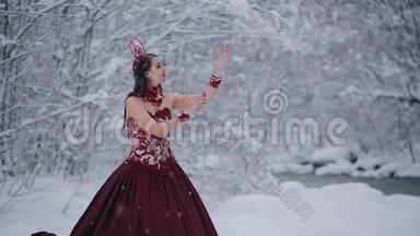 穿着红色<strong>皇室</strong>礼服的童话形象可爱的年轻女子站在雪地里