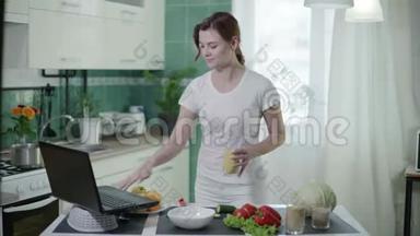 在线食谱中，年轻女子在做沙拉的时候用勺子测量麦粥，然后看着笔记本电脑在屏幕上显示