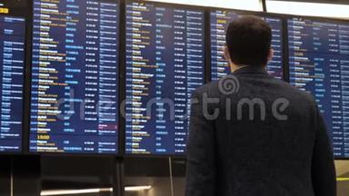 旅客在机场看时刻表板屏幕，国际航班，商务人员出国旅游。