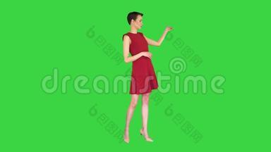 漂亮的女人穿着裙子说话和做手势，就像在绿色屏幕上的<strong>天气预报</strong>，色度键。
