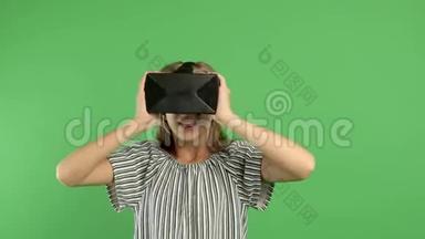 一个可爱的年轻女孩使用<strong>交互</strong>式VR耳机，惊讶和享受虚拟现实。 带着VR眼镜或头盔