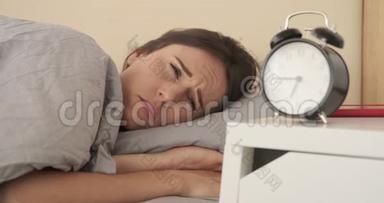 女人从闹钟里醒来，在床上检查她的手机