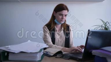 病毒传播，一名戴着医用口罩的不健康妇女在办公室的电脑上工作，一名生病的女商业雇员