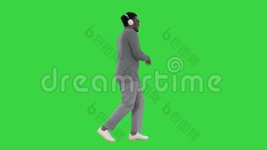 美国业余年轻人戴着耳机走在绿色屏幕上，Chroma键。