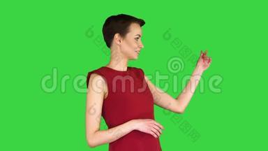 漂亮的女人穿着裙子说话和做手势，就像在绿色屏幕上的天气预报，Chroma键。