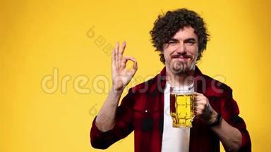 圣帕特里克节。 年轻的啤酒节男子提供大啤酒杯与饮料隔离在黄色背景。 他还好