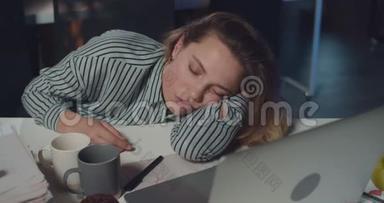 关闭疲惫的女上班族睡在打开的笔记本电脑前。 劳累过度的年轻女商人睡着了
