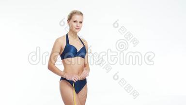 年轻，漂亮，<strong>身材</strong>匀称，金发碧眼的女人穿着蓝色泳衣，在与世隔绝的白色背景下测量她完美的<strong>身材</strong>