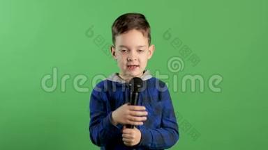 在绿灯背景下，男孩对着麦克风唱歌的肖像，时尚酷人，<strong>儿童娱乐</strong>，开始