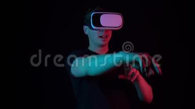 戴着VR眼镜的年轻人。 <strong>一个</strong>沉浸<strong>在</strong>虚拟现实中的人用手做动作。 蓝色和红色的光<strong>落在</strong>