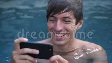 在游泳池里用智能手机<strong>观看视频</strong>的微笑年轻人特写