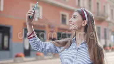 年轻美丽的白种人女孩，棕色头发，头带着她的智能<strong>手机制作</strong>视频信息和吹气
