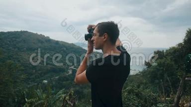 游客在山上拍摄风景如画的风景。 男子游客在户外用相机拍照。 专业人员