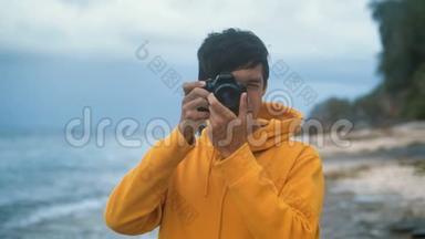 晚上，穿黄色连帽衫的男<strong>摄影</strong>师在美丽的<strong>热带</strong>海滩上拍照