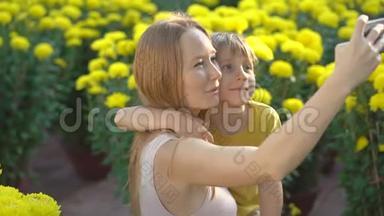 一位年轻的女士和她的儿子在许多黄色的花朵中自拍，<strong>东亚人</strong>为了庆祝一个