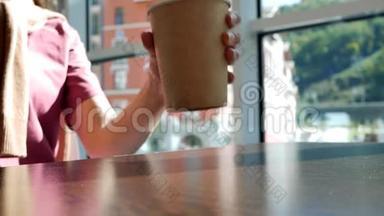 年轻女子从桌子上拿起咖啡馆里的纸杯茶。 喝茶，把杯子放在桌子上