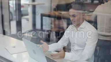 快乐的年轻商人坐在一张桌子上，在一家咖啡馆里用笔记本电脑工作。 赢家看<strong>手</strong>提电脑显示是的<strong>手</strong>势