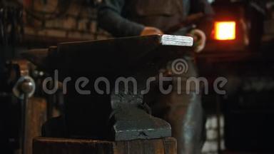 <strong>锻造</strong>工业-一个铁匠把他的仪器放在铁砧上，看着摄像机