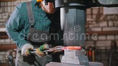 锻造工业-一个铁匠把铁块置于大型工业锻造机的压力之下