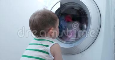 可爱的小男孩看着洗衣机里。 气缸旋压机.. 工业概念洗衣机