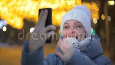 一位女游客在冬季公园里对着花环与家人通过视频通话。