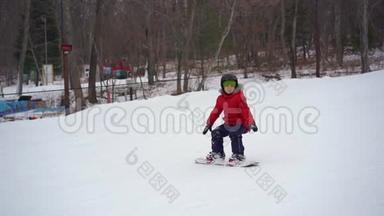 这个小男孩在滑雪板的第一课上<strong>摔倒了</strong>。 冬季活动概念。 慢镜头