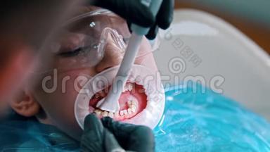 一个小男孩在现代牙科中进<strong>行清</strong>洁治疗-用吸管从口腔中收集水。