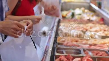 肉类部门的超市里的买家正在挑选袋子里的肉来<strong>称重</strong>和购买。 人们买肉