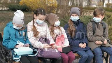 带医疗口罩的学龄儿童坐在长凳上