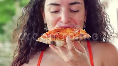 年轻可爱的意大利女人穿着红色连衣裙，在餐馆里急切地吃和享受意大利披萨。 这就是