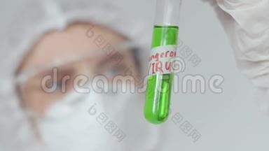 一个戴<strong>防</strong>护<strong>眼镜</strong>和医用口罩的女孩检查一个装有绿色液体标记的危险病毒的试管