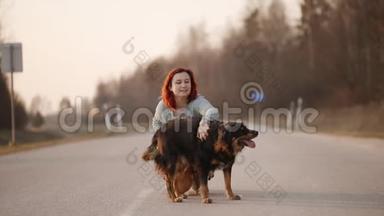 年轻的红发女人在路中间日落时和<strong>贱</strong>狗玩耍。 慢动作