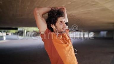 一位微笑的运动员的肖像，年轻人在耳机上听音乐，做伸展运动，在下面热身