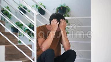 痛苦悲伤和沮丧的年轻人独自坐在家里的楼梯上：痛苦悲伤的人。