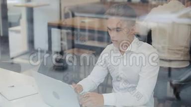 快乐的年轻商人坐在一张桌子上，在一家咖啡馆里用笔记本电脑工作。 赢家看<strong>手</strong>提电脑显示是的<strong>手</strong>势