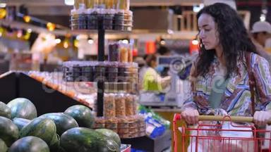 漂亮的年轻女人或母亲在<strong>超市</strong>购物，选择食物西瓜、鳄梨、<strong>水果</strong>、胡萝卜