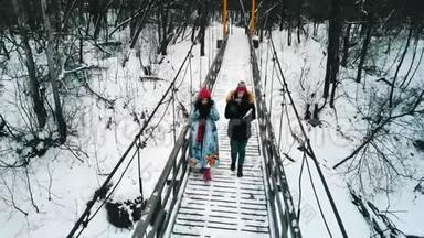 在冬天的森林里，两个年轻的女朋友在雪桥上喝着热水瓶里的热饮料